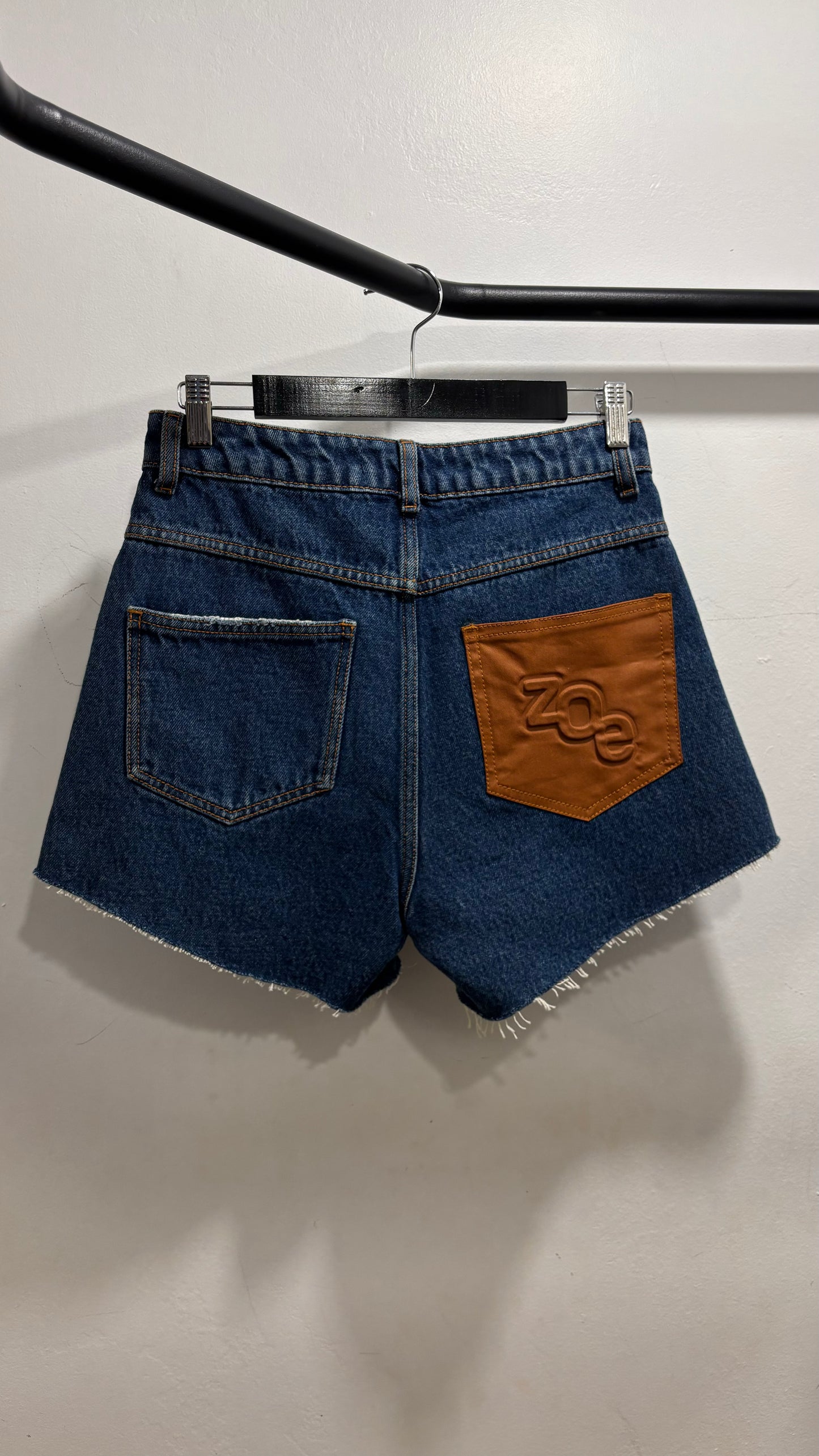 Shorts jeans escuro detalhe marrom no bolso